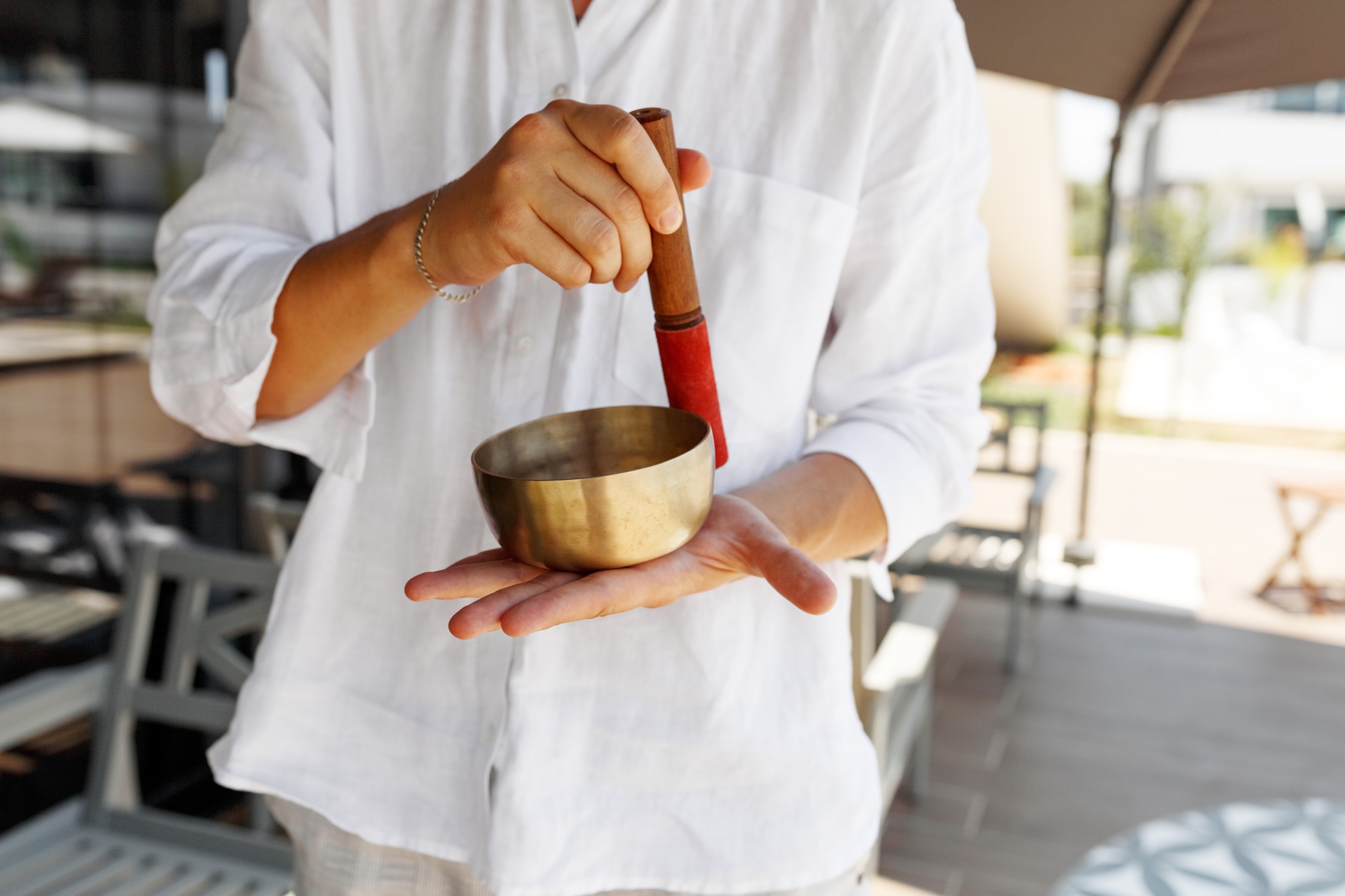 Man hands using singing bowl in sound healing therapy outdoors, closeup